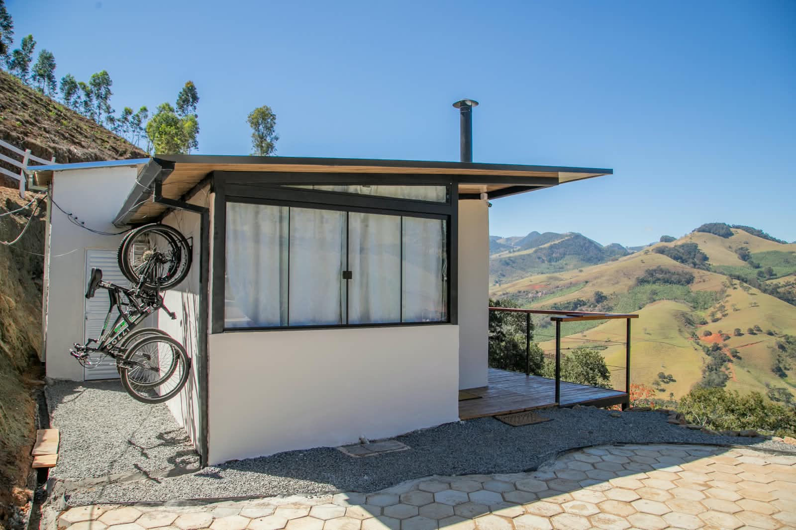 Deck externo com bicicletas na parede e as montanhas do Sul de Minas ao fundo